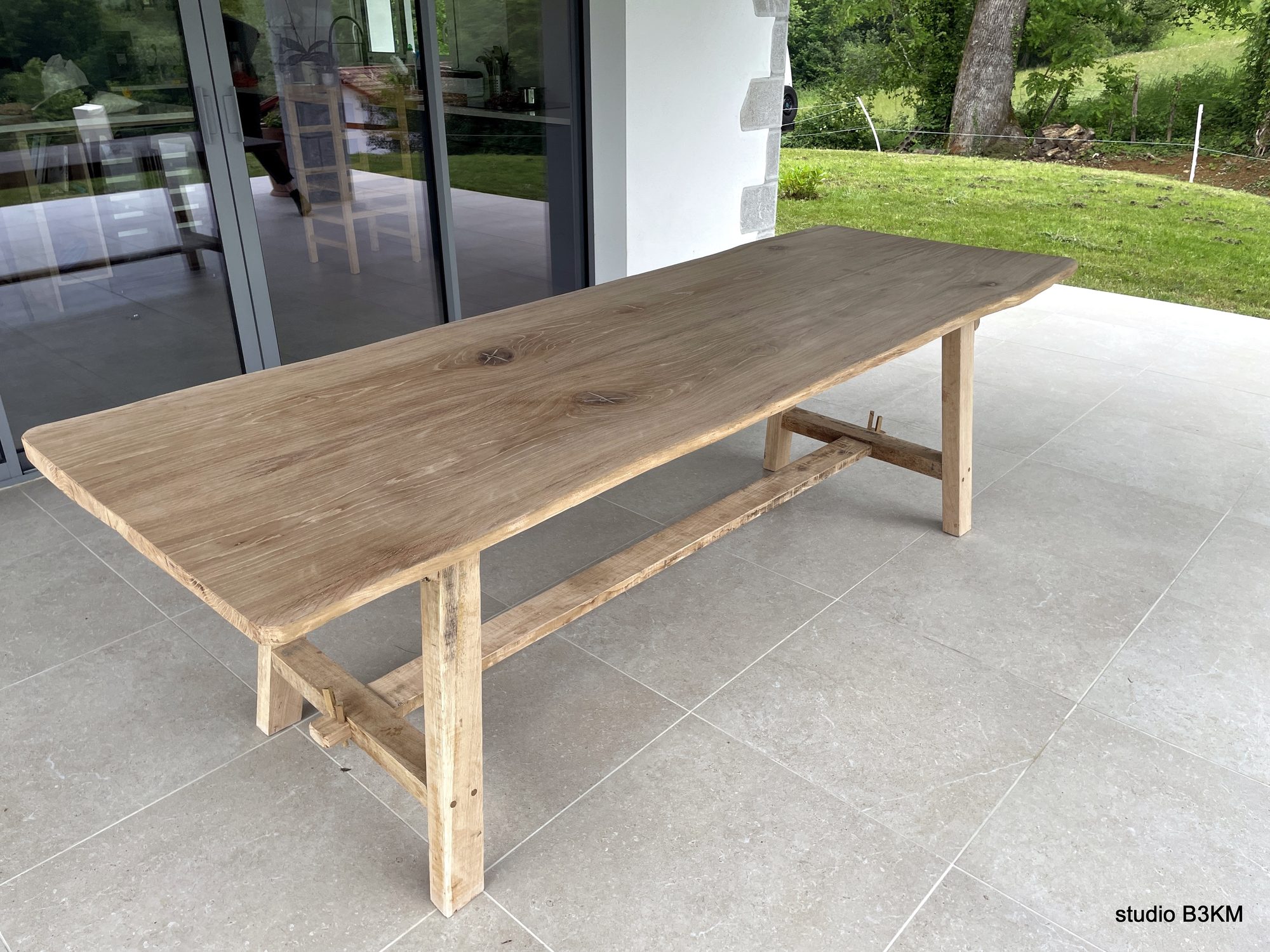 Long solid oak table on a terrace by B3KM EcoDesign
